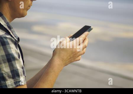 Mann mit Smartphone auf der Straße, Nahaufnahme. Konzept der digitalen Kommunikation, moderner urbaner Lebensstil, Navigation, Warten im öffentlichen Raum Stockfoto