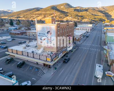 Ely, Vereinigte Staaten - 06. November 2024: Aus der Vogelperspektive des Nevada Hotels und der Spielhalle werfen einen langen Schatten über die leeren Straßen, ein lebendiges Wandgemälde an der Seite. Stockfoto
