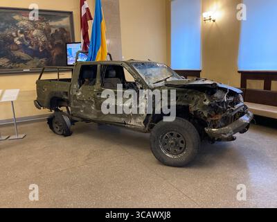 Ein zerstörter Pickup-Truck aus dem Russland-Ukraine-Krieg, ausgestellt in einem Rigaer Museum, präsentiert als Relikt und Gedenkstätte aus Kriegszeiten. Stockfoto
