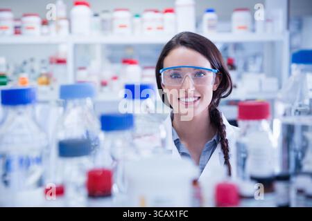 Reagenzflaschen und Glaskolben liegen auf einem übersichtlichen Labortisch mit farbigen Schraubverschlüssen Stockfoto