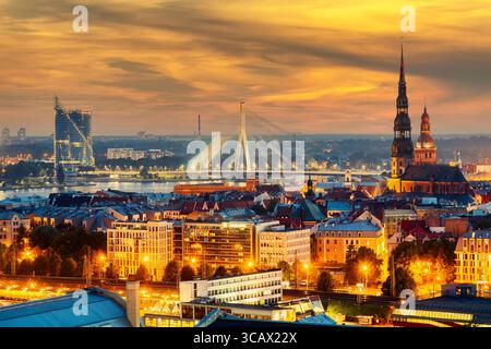 Wunderschönes Panorama von Riga Zentrum und Vansu Brücke über den Daugava Fluss während des atemberaubenden Sonnenuntergangs. Blick auf die beleuchtete Stadt Riga, die Hauptstadt von Lettland Stockfoto