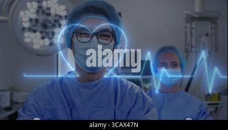 Reife Chirurgen in Peelings, die EKG-Kurve und Herzgrafik beobachten, unter ODER Licht und Monitore Stockfoto