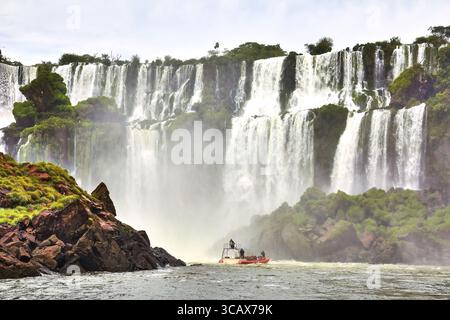 Die majestätischen Wasserfälle von Iguazu kaskadieren über üppige Klippen mit einem Boot in der Szene Stockfoto