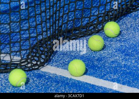 Vier Padelbällchen neben dem Netz auf einem blauen Platz. Ein Padel Court Detail Stockfoto