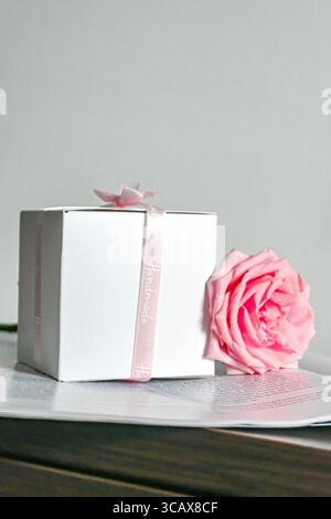 Eine elegante Geschenkbox mit einer wunderschönen Rose auf einem stilvollen Tisch Stockfoto