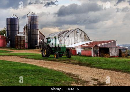 Mantua, Ohio – 15. Oktober 2017: Ein John Deere-Traktor sitzt auf einem Bauernhof im Leerlauf. Silos und Scheunen stehen im Hintergrund und zeigen das ländliche Leben und die Landwirtschaft Stockfoto