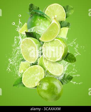 Frische Limetten und Spritzwasser in der Luft vor grünem Hintergrund Stockfoto