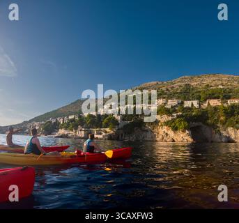 Dubrovnik, Kroatien - 12. September 2023: Touristen genießen eine geführte Kajaktour bei Sonnenuntergang entlang der Küste, paddeln in bunten Kajaks. Stockfoto