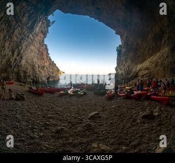 Dubrovnik, Kroatien - 12. September 2023: Kajakfahrer sammeln sich in einer Höhle während einer Tour bei Sonnenuntergang. Die Leute schwimmen und bereiten sich auf den Start vor. Stockfoto