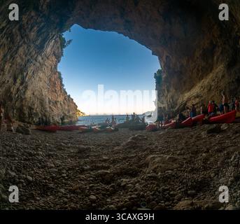 Dubrovnik, Kroatien - 12. September 2023: Kajakfahrer sammeln sich in einer Höhle während einer Tour bei Sonnenuntergang. Die Menschen ruhen sich aus und genießen die Landschaft. Stockfoto