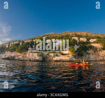 Dubrovnik, Kroatien - 12. September 2023: Ein Kajakfahrer genießt eine Tour bei Sonnenuntergang entlang der Küste. Das ruhige Wasser reflektiert das goldene Licht. Stockfoto