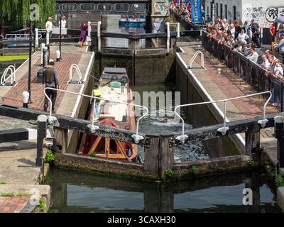 Ein Blick aus der Höhe auf ein Schmalboot, das durch die berühmte Doppelkanalschleuse am Camden Lock in Camden Town, London, Großbritannien fährt. Stockfoto