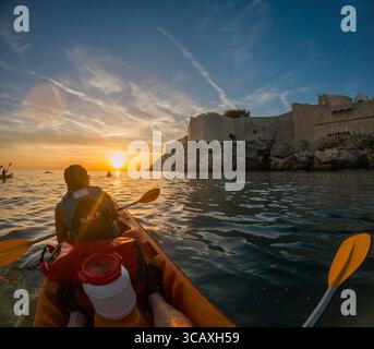Dubrovnik, Kroatien - 12. September 2023: Kajakfahrer paddeln während einer Führung in den Sonnenuntergang in der Nähe der Stadtmauern. Genießen Sie die Schönheit von Dubrovnik. Stockfoto
