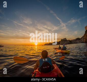 Dubrovnik, Kroatien - 12. September 2023: Kajakfahrer genießen eine Tour bei Sonnenuntergang in der Nähe der Stadtmauern. Paddeln Sie in den Sonnenuntergang und erleben Dubrovnik. Stockfoto