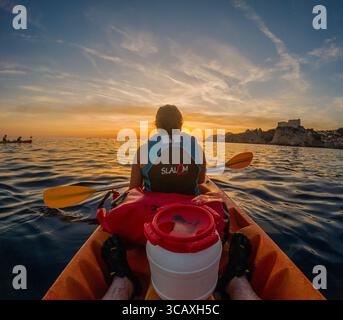 Dubrovnik, Kroatien - 12. September 2023: Ein Kajak genießt eine Tour bei Sonnenuntergang und paddelt zum Horizont mit der Silhouette der Stadt in der Ferne. Stockfoto