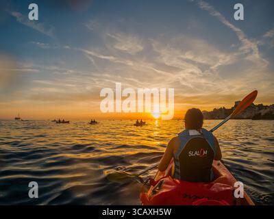 Dubrovnik, Kroatien - 12. September 2023: Kajakfahrer paddeln auf einer geführten Tour in den Sonnenuntergang. Sie genießen die wunderschöne Landschaft und das ruhige Wasser. Stockfoto