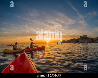 Dubrovnik, Kroatien - 12. September 2023: Kajakfahrer genießen eine Tour bei Sonnenuntergang in der Nähe der Stadtmauern. Stockfoto