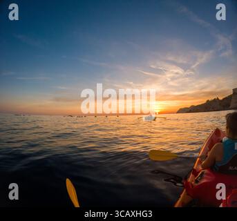 Dubrovnik, Kroatien - 12. September 2023: Touristen genießen eine geführte Kajaktour bei Sonnenuntergang vor der Küste von Dubrovnik, Kroatien, während sie in den Sonnenuntergang paddeln. Stockfoto