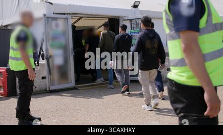 HINWEIS FÜR DIE REDAKTION: FILMMATERIAL IST AN DER QUELLE VERSCHWOMMEN. Screenshot aus dem Video des Innenministeriums der Grenzschutzbeamten, das die ersten kleinen Migranten verarbeitet, die im Rahmen des neuen britischen „One in, One Out“-Deals bei Western Jet Foil in Dover, Kent festgehalten wurden. Die Migranten, die am Tag der Inbetriebnahme des Pilotprogramms inhaftiert wurden, durchlaufen in den letzten 24 Stunden die ersten Phasen des Pilotprozesses für die Rückkehr zwischen Großbritannien und Frankreich, einschließlich der Erstbearbeitung, biometrischer und Sicherheitskontrollen sowie der Umsiedlung in das Abschiebungszentrum für Einwanderer, um auf ihre Rückkehr nach Frankreich zu warten. Bilddatum: Donnerstag, 7. August, Stockfoto