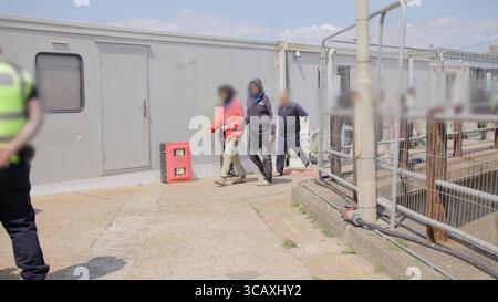 HINWEIS FÜR DIE REDAKTION: FILMMATERIAL IST AN DER QUELLE VERSCHWOMMEN. Screenshot aus dem Video des Innenministeriums der ersten Migranten mit kleinen Booten, die im Rahmen des neuen britischen „One in, One Out“-Deals bei Western Jet Foil in Dover, Kent festgehalten wurden. Die Migranten, die am Tag der Inbetriebnahme des Pilotprogramms inhaftiert wurden, durchlaufen in den letzten 24 Stunden die ersten Phasen des Pilotprozesses für die Rückkehr zwischen Großbritannien und Frankreich, einschließlich der Erstbearbeitung, biometrischer und Sicherheitskontrollen sowie der Umsiedlung in das Abschiebungszentrum für Einwanderer, um auf ihre Rückkehr nach Frankreich zu warten. Bilddatum: Donnerstag, 7. August 2025. Stockfoto