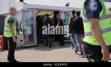 HINWEIS FÜR DIE REDAKTION: FILMMATERIAL IST AN DER QUELLE VERSCHWOMMEN. Screenshot aus dem Video des Innenministeriums der Grenzschutzbeamten, das die ersten kleinen Migranten verarbeitet, die im Rahmen des neuen britischen „One in, One Out“-Deals bei Western Jet Foil in Dover, Kent festgehalten wurden. Die Migranten, die am Tag der Inbetriebnahme des Pilotprogramms inhaftiert wurden, durchlaufen in den letzten 24 Stunden die ersten Phasen des Pilotprozesses für die Rückkehr zwischen Großbritannien und Frankreich, einschließlich der Erstbearbeitung, biometrischer und Sicherheitskontrollen sowie der Umsiedlung in das Abschiebungszentrum für Einwanderer, um auf ihre Rückkehr nach Frankreich zu warten. Bilddatum: Donnerstag, 7. August, Stockfoto