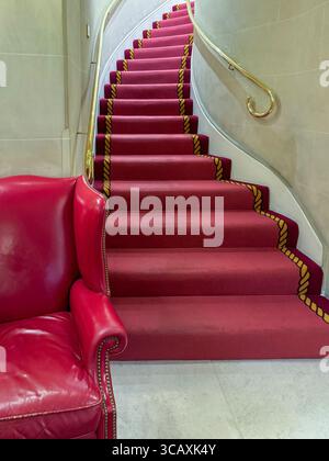 Eine elegante geschwungene Treppe mit einem luxuriösen dunkelroten Teppich im weltberühmten Ritz Hotel in Mayfair, London, Großbritannien. Stockfoto