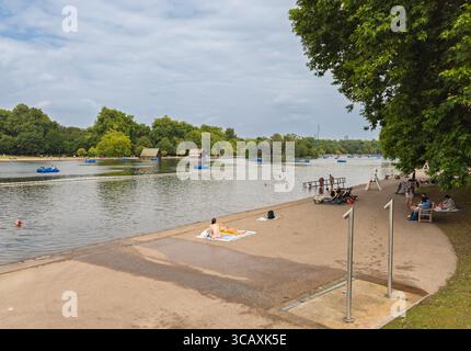 Im Serpentine Lido im Hyde Park, einem beliebten Outdoor-Badeort in London, Großbritannien, schwimmen und sonnen Sie sich an einem Sommertag. Stockfoto
