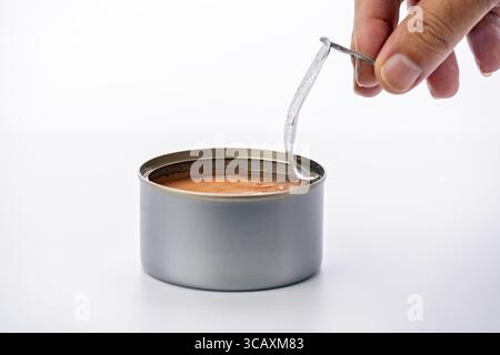 Öffnen der Metalldose Thunfisch in Salzlake mit Händen auf weißem Hintergrund Stockfoto