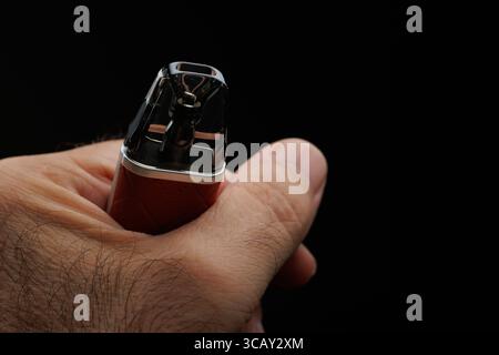 Hand einer nicht erkennbaren Person, die elektronische Zigarette auf schwarzem Hintergrund hält Stockfoto
