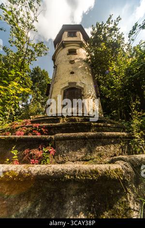 Alter verlassener Turm, umgeben von üppigem Grün und Steintreppen in Deutschland Stockfoto