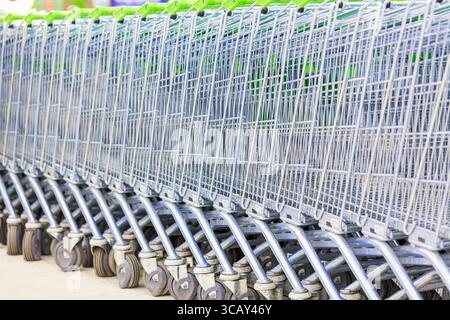 Auf einem Parkplatz in der Nähe eines Supermarktes im Freien gibt es viele Einkaufswagen aus Metall. Einkaufskonzept Stockfoto