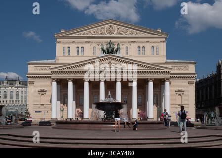 Das Bolschoi-Theater in Moskau mit seiner ikonischen neoklassizistischen Fassade und dem Brunnen, das an einem sonnigen Tag festgehalten wird und Besucher die Szene genießen Stockfoto