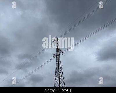 Stromkabel und Strommasten vor grauem bewölktem Himmel. Stockfoto