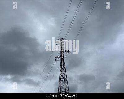 Stromkabel und Strommasten vor grauem bewölktem Himmel. Stockfoto