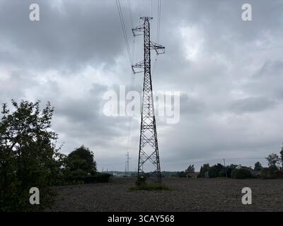 Stromkabel und Strommasten vor grauem bewölktem Himmel. Stockfoto