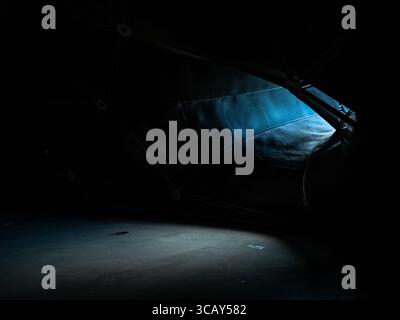 Dunkles abstraktes Interieur mit stimmungsvollem blauen Licht und geometrischen architektonischen Elementen, die eine geheimnisvolle Atmosphäre schaffen Graz Museum Stockfoto