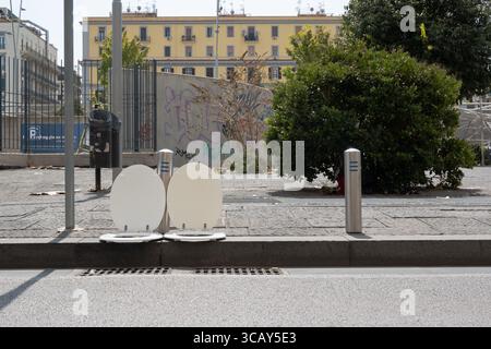 Urbane Straßenszene in Neapel mit zwei weißen Toilettensitzen auf einem Bürgersteig mit Graffitis und Wohngebäuden im Hintergrund Stockfoto