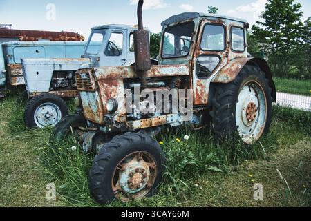 Rostige Traktoren aus der Sowjetzeit im Feld aufgegeben – Landmaschinenverfall Stockfoto