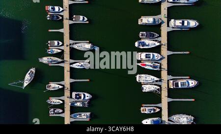 Blick von oben auf Yachthafen - Boote liegen am Pier auf ruhigem Wasser an Stockfoto