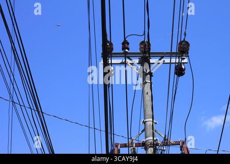 Elektrischer Pol mit einigen elektrischen Kabeln auf einem hellblauen Hintergrund. Stockfoto