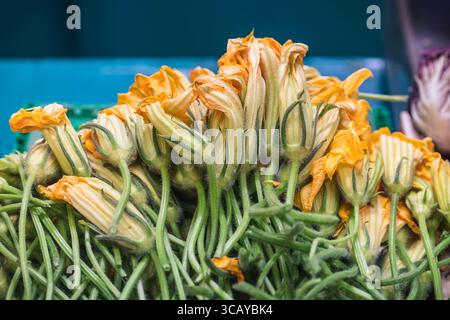 Frische Zucchini-Blumen werden an einem Marktstand ausgestellt. Eine delikate und saisonale Zutat, die häufig in der mediterranen und italienischen Küche verwendet wird Stockfoto