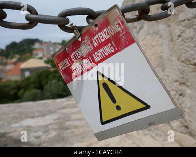 Gefahrenhinweis in mehreren Sprachen hängt am Reiseziel Stockfoto