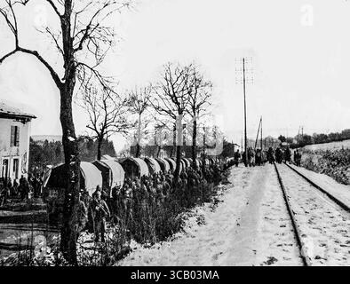 Szene in der Nähe von Verdun während der Schlacht im Februar 1916: Eine Linie von Militärfahrzeugen transportiert französische Truppen an die Front, während leicht verwundete Soldaten über den schneebedeckten Eisenbahnweg zu Feldambulanten zurückkehren. Dieser krasse Moment der Kriegszeit spiegelt die unnachgiebige Logistik der Schlacht von Verdun wider. Veröffentlicht in LíIllustration, 1. April 1916. Stockfoto
