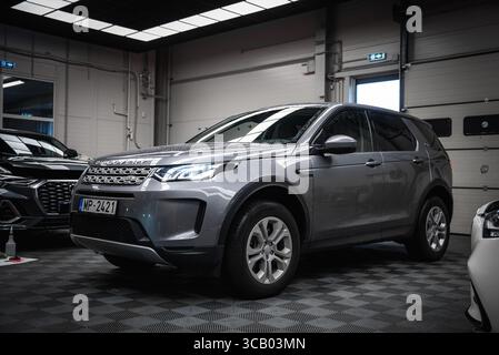 Silber Land Rover Discovery in moderner Garage mit Luxusautos Stockfoto