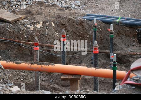 Ein Haufen Rohre sind im Dreck, einige davon sind orange Stockfoto