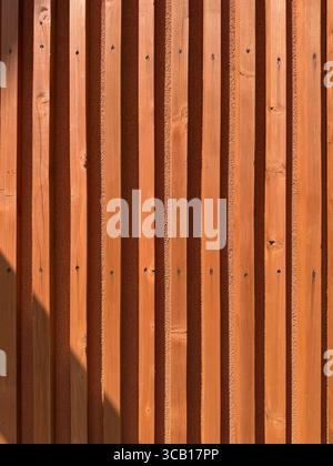 Skandinavische Holzfassade mit vertikalen Lamellen und minimalistischem Design warme Naturtöne klare Linien Sonnenlicht Textur Moderne Architektur Inspiration Stockfoto