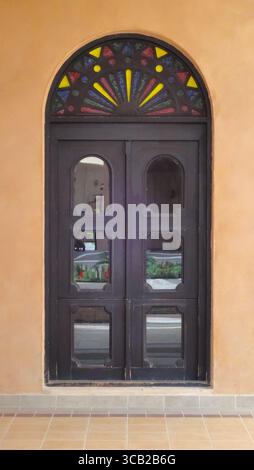 Eine verzierte traditionelle Holztür mit einem lebendigen Buntglasfanlight im Katara Cultural Village, Doha. Stockfoto