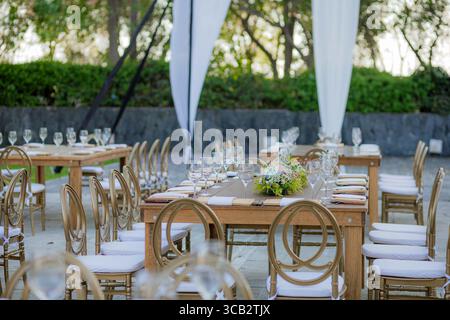 Holztisch mit Kristallgläsern und Blumenmotiv, im Freien für eine Hochzeit oder elegante Feier. Stockfoto