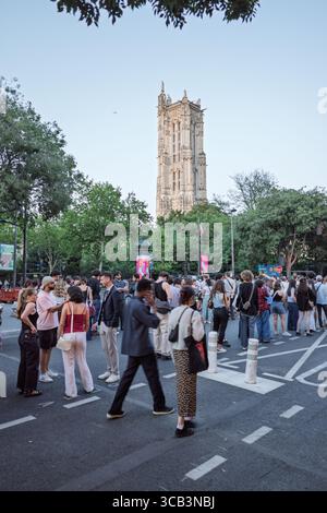 In der Abenddämmerung versammelt sich eine große Menschenmenge in der Nähe des historischen Saint-Jacques-Turms in Paris, Frankreich, um eine lebhafte urbane Szene zu schaffen. Stockfoto