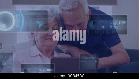 Erkunden Sie ältere Ehepaare, die mit einem Tablet auf einem Wohnzimmersofa interagieren, mit digitaler Überlagerungsgrafik Stockfoto